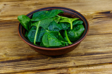 Fresh green spinach leaves in bowl on a wooden table