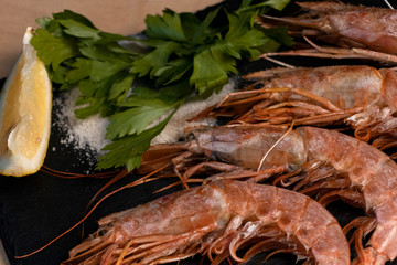 Large oceanic shrimps fried with lemon and parsley on a black stone board. Yummy