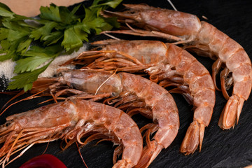 Large oceanic shrimps fried with lemon and parsley on a black stone board. Yummy