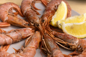 Large tiger prawns on a plate with lemon wedges. Kitchen.