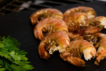 Large oceanic shrimps fried with lemon and parsley on a black stone board. Sea food.