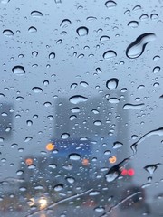 Rain drops on the window. Abstract background. Wet the car window with the background of the night city traffic and traffic congestion concept.