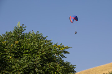 Blue Paraglider flying into the sky with clouds in a sunny day. paragliding man, paragliding...