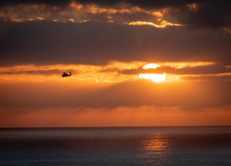 A Blackhawk helicopter banking left awawy from the sun during a training mission at sunset 