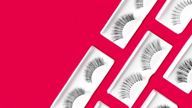 Fake eyelashes on trendy bright neon multicolored background. Backdrop changes color. Pink, blue. Beauty pattern. Makeup accessories. Cosmetic products. Banner. Stop motion animation. Looping video. 