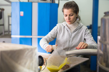 Confident workwoman controlling quality of olive oil of traditional cold pressing on artisanal...