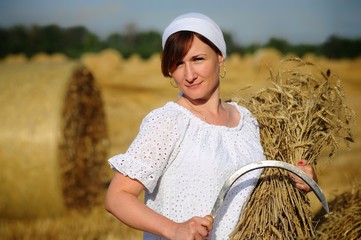 A peasant girl in a white dress and a scarf harvesting wheat with a sickle and an armful of wheat ears in her hands