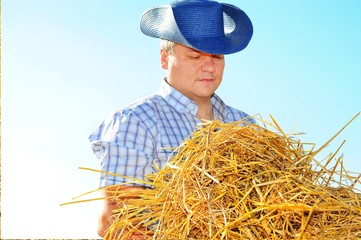 Man cowboy in hat on the farm is doing work and collecting hay