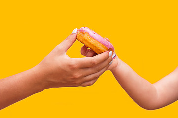 female hand passes a pink delicious donut to a child's hand.  delivery