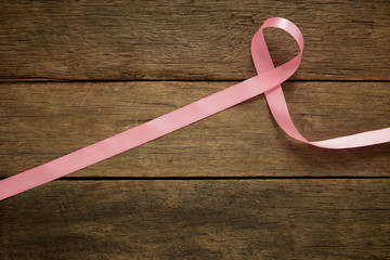 Pink ribbon on wooden breast cancer awareness background concept