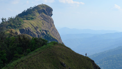 Backpacker standing on the mountain ridge looking out to the mountain range scenic view