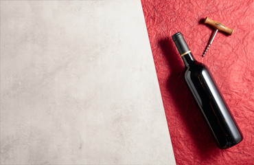 A bottle of red wine on red crumpled paper.