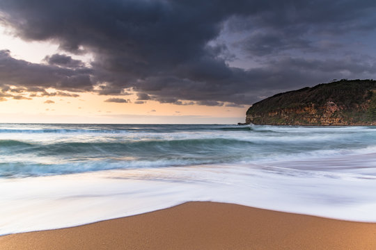 Sunrise at the beach with waves and clouds