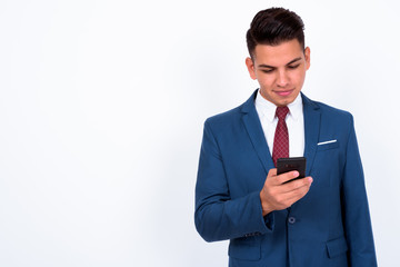 Portrait of young handsome multi ethnic businessman in suit using phone