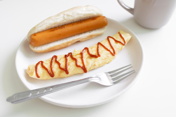 Simple easy breakfast of omelette and sausage served on white dish.