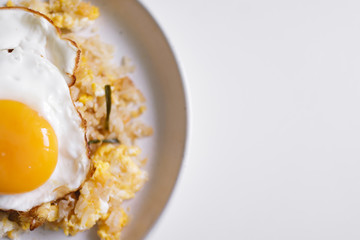 Homemade fried rice with fried egg on top served on white dish.
