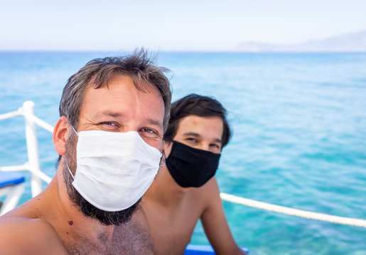 Man and boy with masks on beach jetty