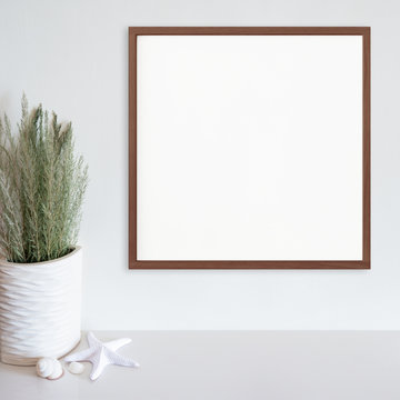 Wood frame mockup on white wall with beach/ocean theme decoration on white surface. Dark wood. Copy space.
