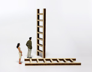 A miniature man and a miniature woman standing in front of another ladder.
