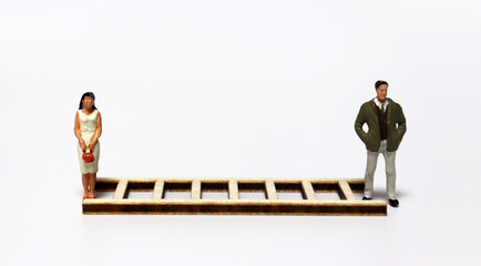 A miniature man and a miniature woman standing in front of another ladder.
