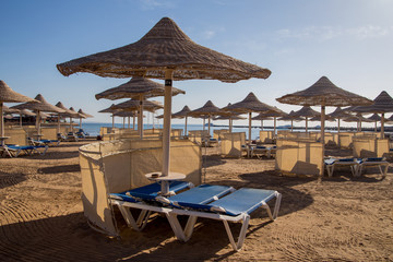 sandy beach with sun loungers thatched umbrellas