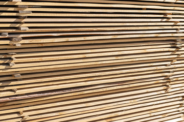 Long wooden planks for construction works in the sawmill. Timber mill.  Raw wood beam, stacked at construction site.