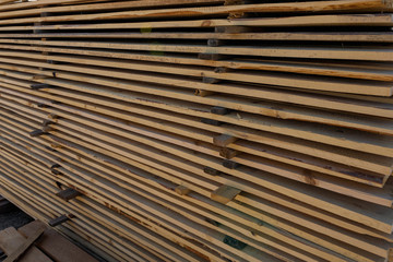 Long wooden planks for construction works in the sawmill. Timber mill.  Raw wood beam, stacked at construction site.