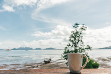 Morning coffee mug with low tide sea view as background.