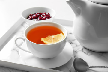 Cup of hot beverage, teapot and jam on table