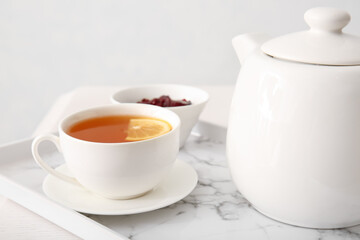 Cup of hot beverage, teapot and jam on table