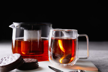 Teapot, cup of hot beverage and cookies on table