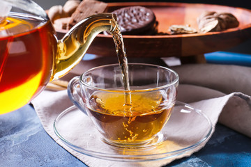 Pouring of hot tea in cup on table