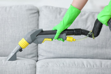 Dry cleaner's employee removing dirt from sofa in house