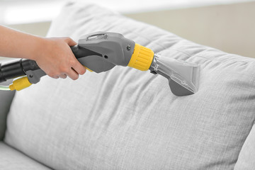 Dry cleaner's employee removing dirt from sofa in house