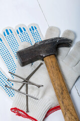 An old hammer, work gloves, and a handful of nails. On white background.