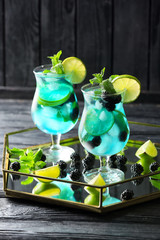 Glasses of tasty blue mojito cocktail on table