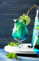 Glass of tasty blue mojito cocktail on color background