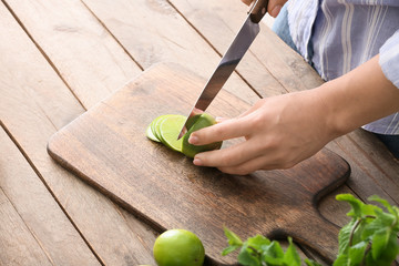 Woman making tasty mojito cocktail at table