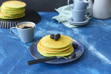 Plate with tasty green pancakes and berries on table