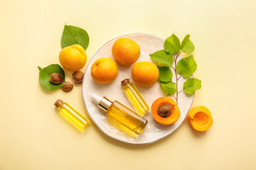 Bottles of apricot essential oil on color background