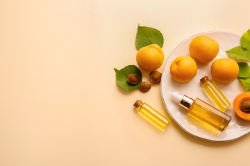 Bottles of apricot essential oil on color background