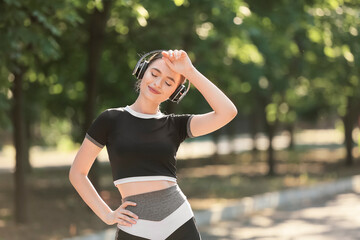 Sporty young woman with headphones resting after running outdoors