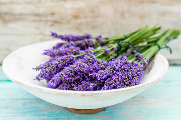 Lavender flowers in a basket on a wooden background.