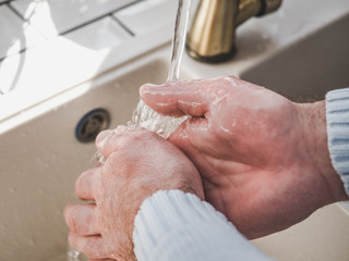 Fototapeta premium Men's hands and a bar of soap on a background of a vintage tap. Top view, closeup. Health Care and Prevention Concept