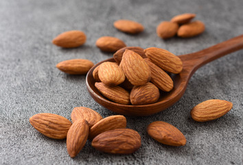 Almonds in wooden spoon on black background,copy space.