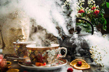 Steaming asian cast iron tea pot with cups 