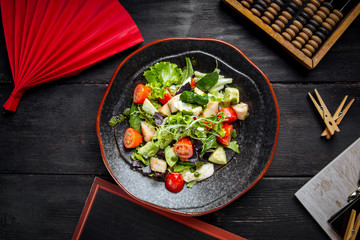 Top view on fresh vegetables salad in black plate