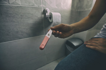 The woman is checking the pregnancy test in the bathroom