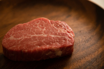 Raw Fillet Mignon Steak on the wooden round plate