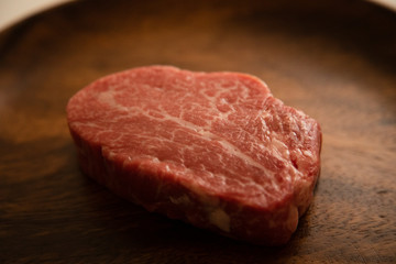 Raw Fillet Mignon Steak on the wooden round plate